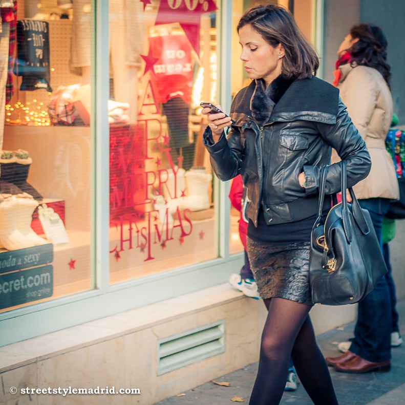 Street Style Madrid, cazadora de cuero negra, con falda de piel negra, medias negras y bolso negro